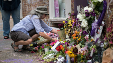 A woman places flowers on a makeshift memorial dedicated to Heather Heyer off the mall in downtown Charlottesville, Virginia, one-year after the violent white nationalist rally where Heyer was killed and dozens of others were injured.
