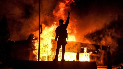 A protester reacts standing in front of a burning building set on fire during a demonstration in Minneapolis, Minnesota, on May 29, 2020, over the death of George Floyd, a black man who died after a white policeman kneeled on his neck for several minutes. - Violent protests erupted across the United States late on May 29 over the death of a handcuffed black man in police custody, with murder charges laid against the arresting Minneapolis officer failing to quell seething anger.