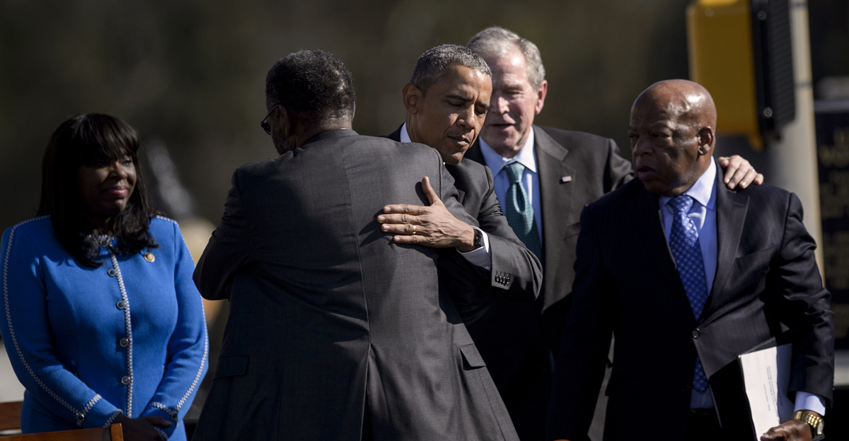 US President Barack Obama hugs Rep. Bobby Rush while former US President George W. Bush and Rep. John Lewis talk at the Edmund Pettus Bridge on March 7, 2015 in Selma, Alabama.