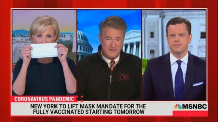 Mika Brzezinksi holds a mask next to Joe Scarborough and Willie Geist