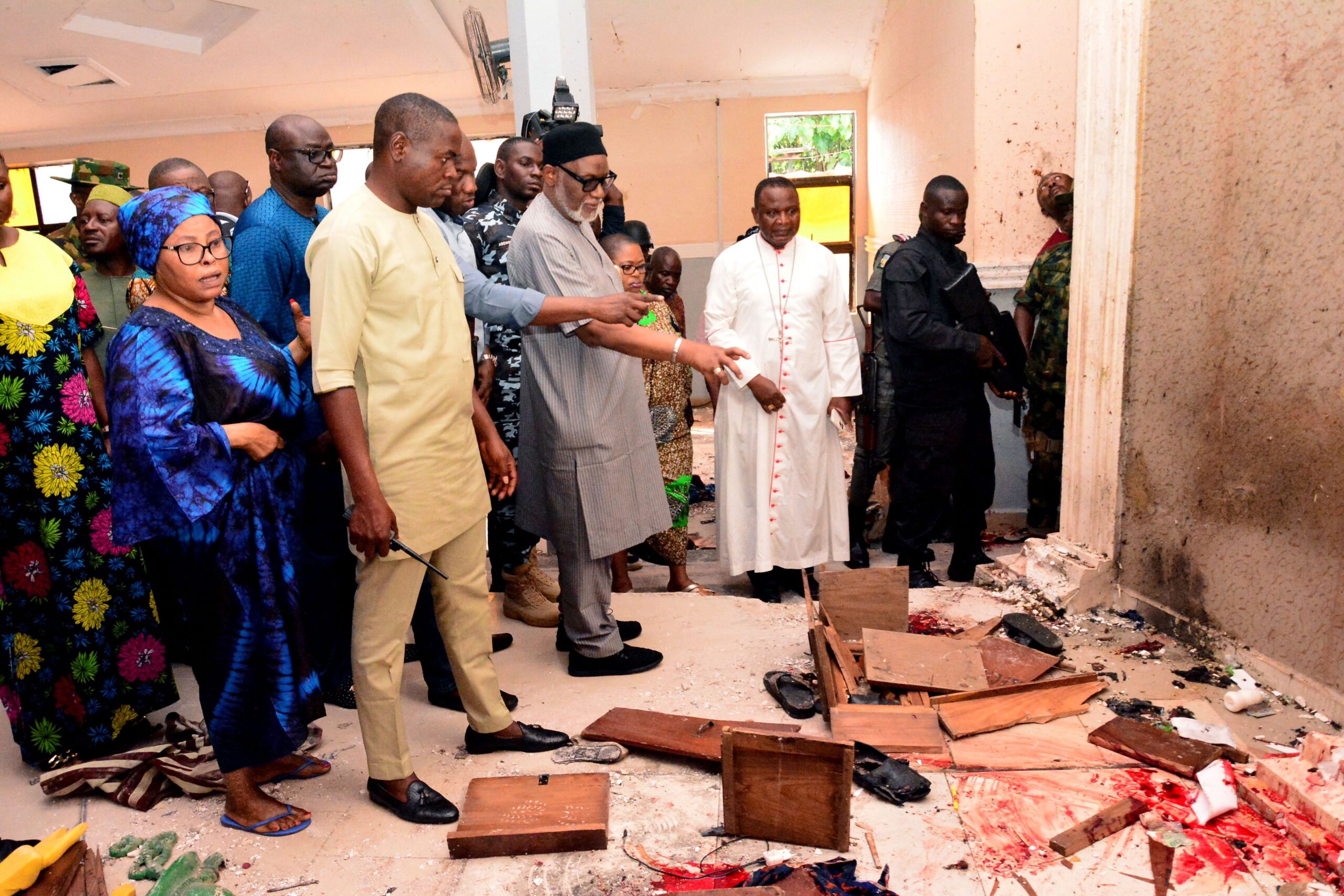 Ondo State governor Rotimi Akeredolu (3rd L) points to blood the stained floor after an attack by gunmen at St. Francis Catholic Church in Owo town, southwest Nigeria on June 5, 2022. - Gunmen with explosives stormed a Catholic church and opened fire in southwest Nigeria on June 5, killing "many" worshippers and wounding others, the government and police said. The violence at St. Francis Catholic Church in Owo town in Ondo State erupted during the morning service in a rare attack in the southwest of Nigeria, where jihadists and criminal gangs operate in other regions.