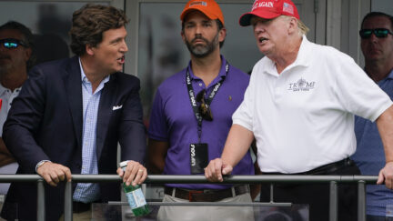 Former President Donald Trump, right, talks with Donald Trump Jr., center, and Tucker Carlson