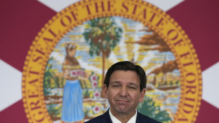 Ron DeSantis standing in front of Florida flag