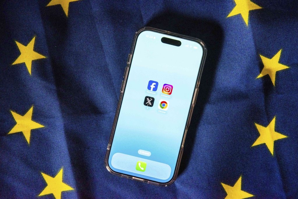 29 July 2025, Belgium, Brüssel: The logos of Facebook, Instagram, X (formerly Twitter) and Google Chrome can be seen on the screen of a smartphone resting on an EU flag. The European Union is making large online platforms and browser providers more accountable with laws such as the Digital Services Act (DSA) and the Digital Markets Act (DMA).