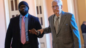 mitch mcconnell grips another man's arm as he walks