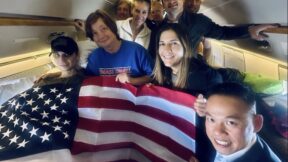 Ill marine Robert gilman and others with a large american flag covering gilman