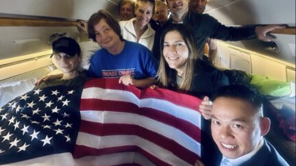 Ill marine Robert gilman and others with a large american flag covering gilman